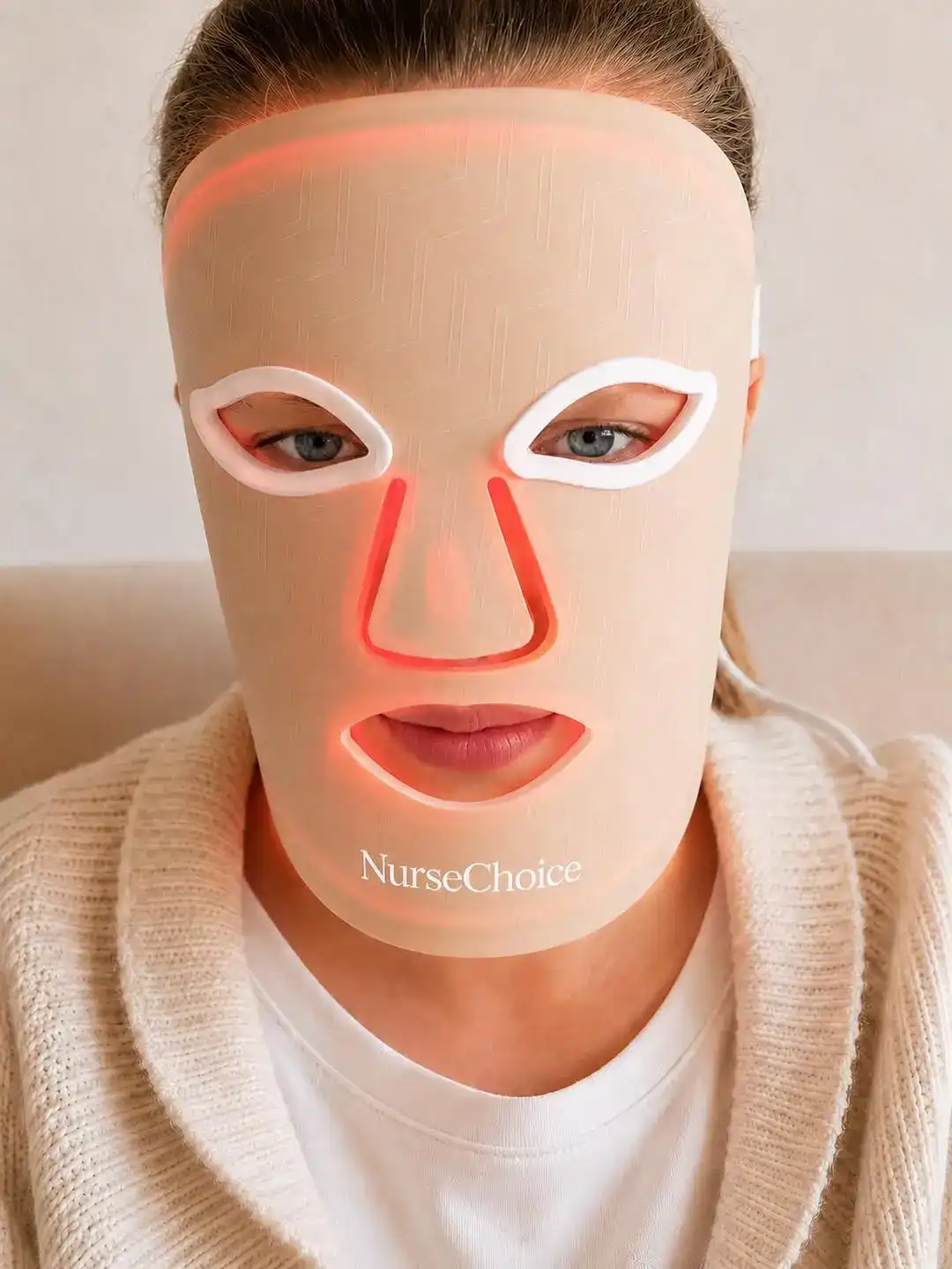 A client wearing a Nurses Choice LED face mask lit red, seated in the clinic