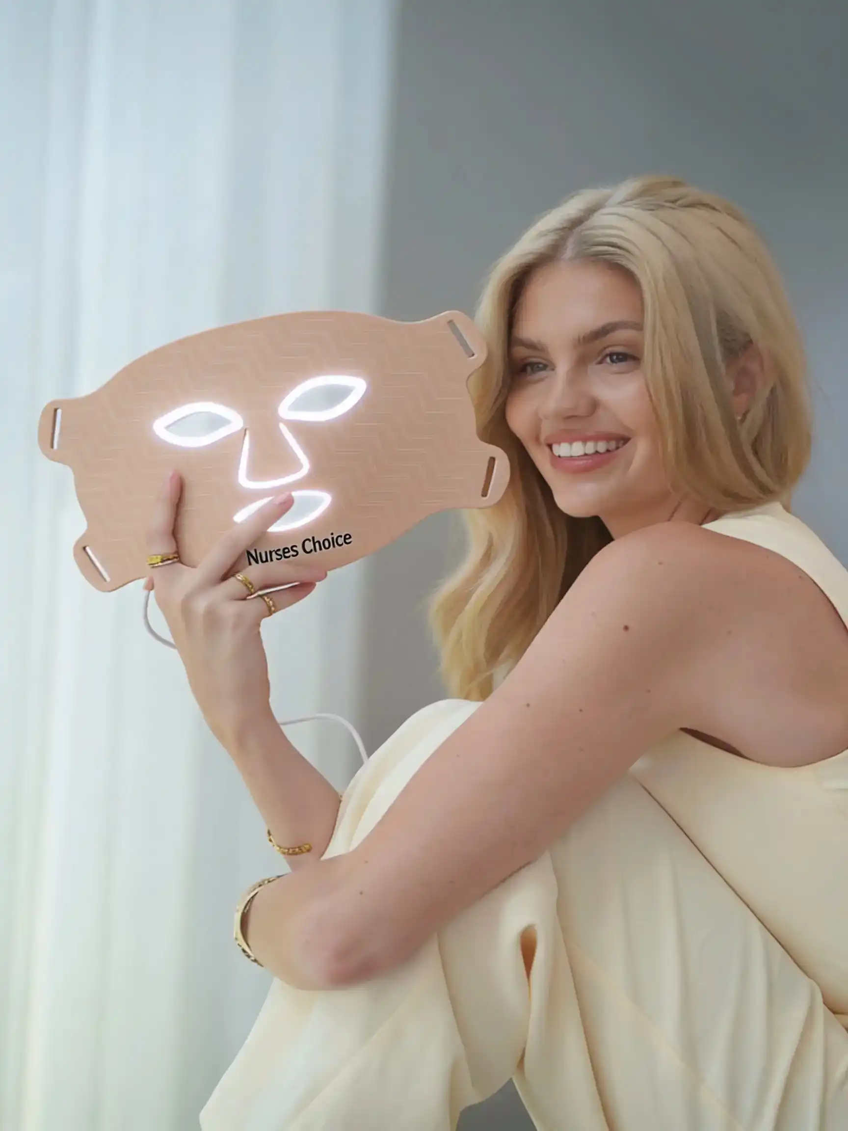 A person holding up an illuminated Nurses Choice LED face mask, the style stocked at the clinic for home use